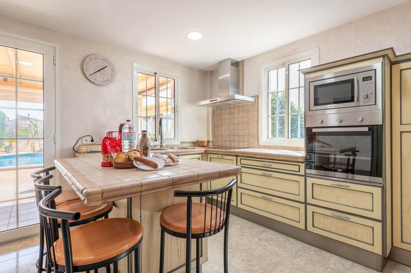 Segunda vista de la cocina con barra de desayuno y salida a la piscina