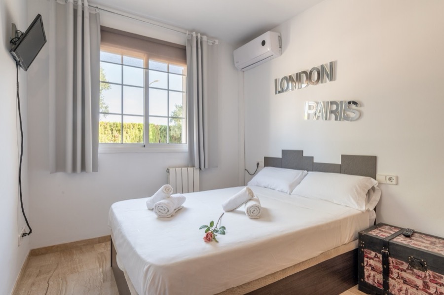 Primer dormitorio con cama doble, aire acondicionado y televisión