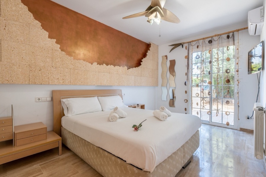 Dormitorio principal con cama doble y salida al jardín